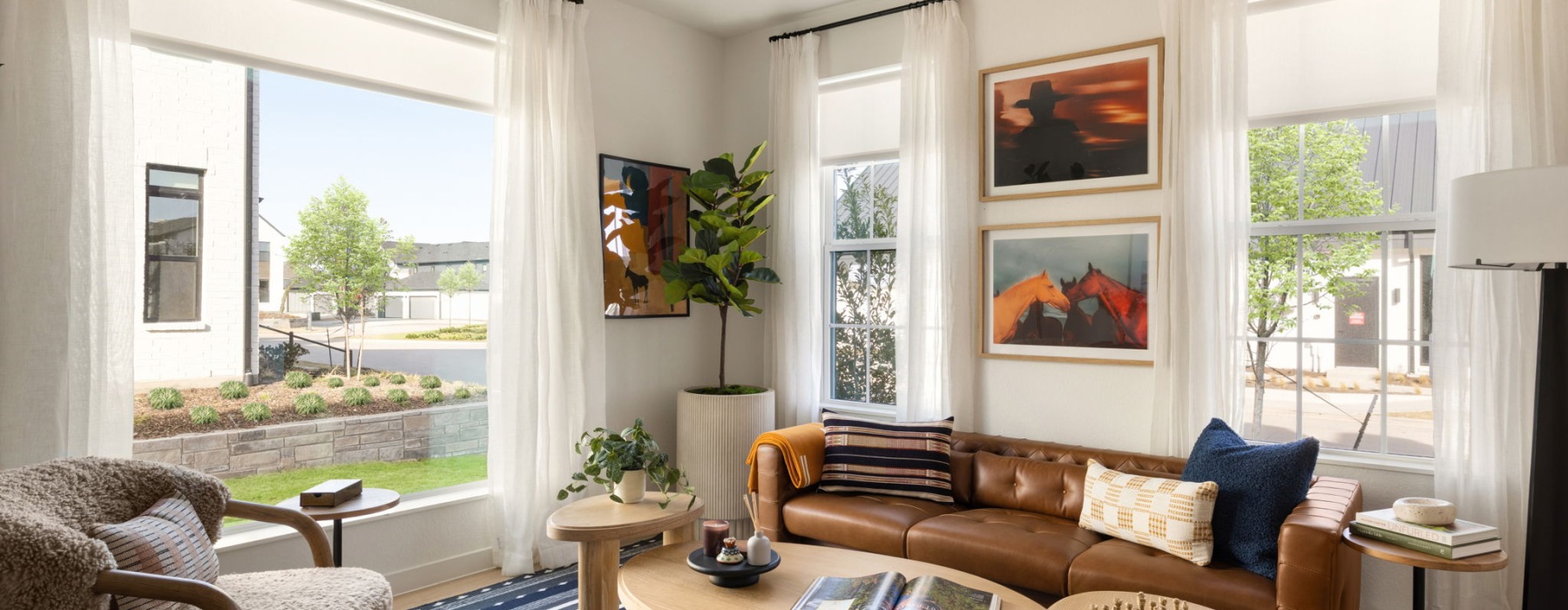 a living room with large windows and a leather couch in a built-to-rent townhome in Frisco